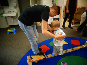 Student helping preschooler on balance beam